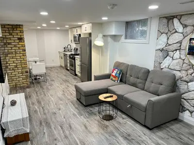 a living room with a couch and a kitchen at Adorable 1 Bedroom Suite With Kitchen Fireplace in Cambridge