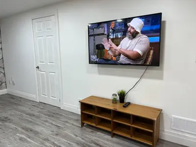 a living room with a tv hanging on a wall at Adorable 1 Bedroom Suite With Kitchen Fireplace in Cambridge