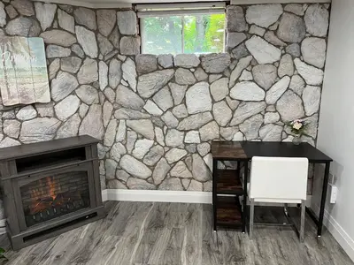 a stone wall in a room with a desk and a fireplace at Adorable 1 Bedroom Suite With Kitchen Fireplace in Cambridge