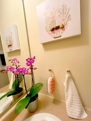 a bathroom with a sink and a mirror and flowers at Stunning Rooms in Townhouse across the Beach in Toronto
