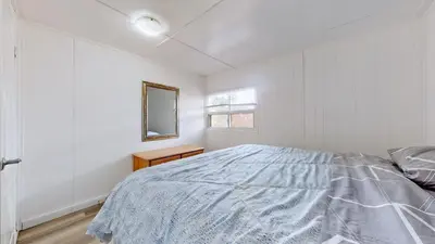 a white bedroom with a bed and a mirror at Main Beach River Retreat - Wasaga Beach 1 - Main Strip - 93 Mosley St in Wasaga Beach