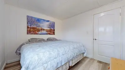 a bedroom with a bed and a painting on the wall at Main Beach River Retreat - Wasaga Beach 1 - Main Strip - 93 Mosley St in Wasaga Beach