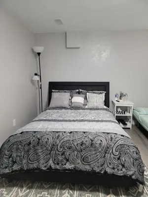 a bedroom with a bed with a black and white bedspread at Falstaff Home in Toronto