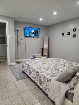 a bedroom with a bed and a flat screen tv on the wall at Falstaff Home in Toronto