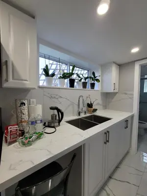 a kitchen with white cabinets and a sink and a window at Falstaff Home in Toronto
