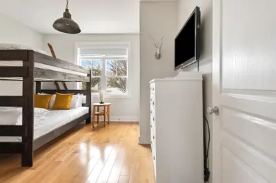 a bedroom with a bunk bed and a flat screen tv at Luxurious Rivergrass Blue Mountain Retreat in Blue Mountains