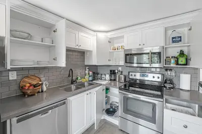 a kitchen with white cabinets and stainless steel appliances at Harbour House in Hamilton