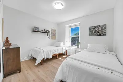 a white bedroom with two beds and a window at Harbour House in Hamilton