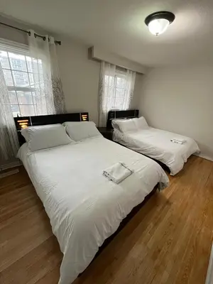 two beds with white sheets in a bedroom at Full Privacy Apartment with Free Parkrings in Toronto