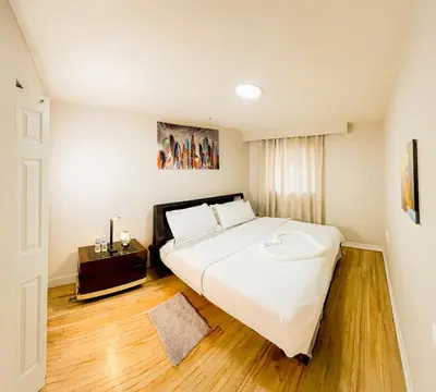 a bedroom with a large white bed and a wooden floor at Full Privacy Apartment with Free Parkrings in Toronto
