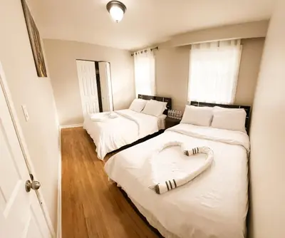 a bedroom with two beds with white sheets and a heart shapedvisoromaly at Full Privacy Apartment with Free Parkrings in Toronto