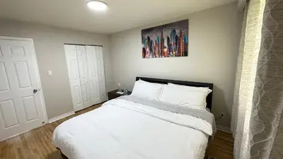 a bedroom with a white bed and a painting on the wall at Full Privacy Apartment with Free Parkrings in Toronto