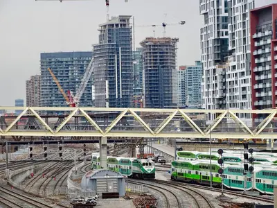 three trains on tracks in a city with tall buildings at Lovely 2 Bed Condo in Downtown Toronto in Toronto
