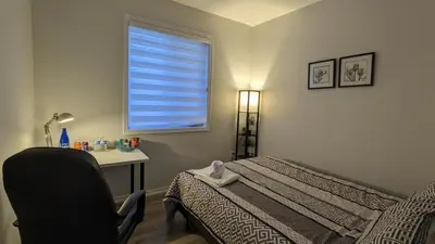a bedroom with a bed and a desk and a window at The Warm Welcome Suite in Thorold