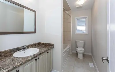 a bathroom with a sink and a toilet and a mirror at The Warm Welcome Suite in Thorold