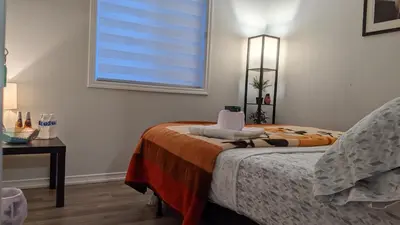 a bedroom with a bed and a window and a table at The Warm Welcome Suite in Thorold