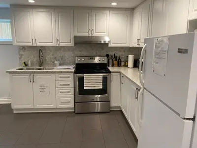 a kitchen with white cabinets and a stove and refrigerator at Yonge and Finch Subway !R Spacious & Stylish Prvt Bdr with Shared Bathroom in Toronto