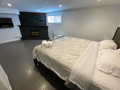 a bedroom with a bed with white sheets and a fireplace at Yonge and Finch Subway !R Spacious & Stylish Prvt Bdr with Shared Bathroom in Toronto