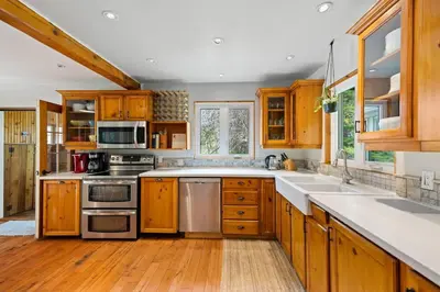 a kitchen with wooden cabinets and stainless steel appliances at Marmora Retreat - Unique Waterfront Farmhouse in Marmora