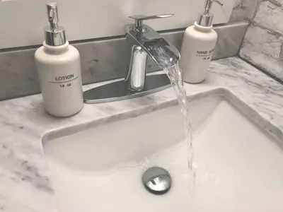 a sink with water coming from a faucet and two soap bottles at Slope-side Studio Bliss Ski-in Ski-out, Renovated At Blue, Hot Tub, Fast Wi-Fi in Blue Mountains