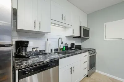 a white kitchen with white cabinets and a sink at The Alpine - Central Collingwood Condo in Collingwood