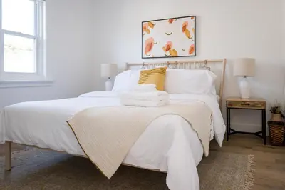 a white bedroom with a bed with white sheets at The Darcie House - cozy, pet-friendly home in PEC in Picton
