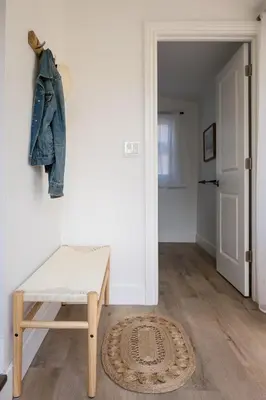 a room with a bench and a jacket hanging on a wall at The Darcie House - cozy, pet-friendly home in PEC in Picton