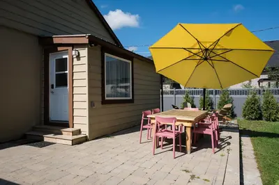 a table and chairs with a yellow umbrella on a patio at The Darcie House - cozy, pet-friendly home in PEC in Picton