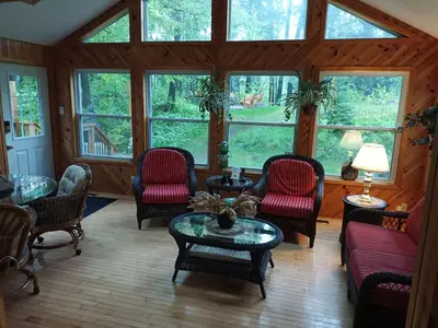 a living room with chairs and a table and windows at Fireside - Waterfront Resort Style Executive Cottage in Kawartha Lakes
