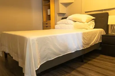 a bedroom with a bed with white sheets and pillows at Cozy Sunset Cottage Overlooking Rice Lake in Roseneath