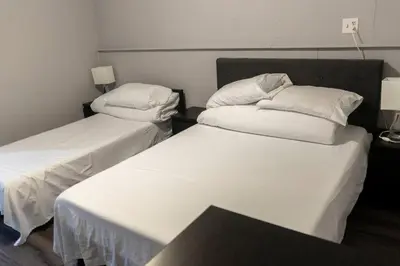 two beds in a room with white sheets and pillows at Cozy Sunset Cottage Overlooking Rice Lake in Roseneath