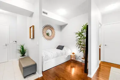 a white bedroom with a bed and a mirror at AOC Suites - High-Rise Condo - City View in Toronto