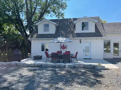 a table and chairs with an umbrella in front of a house at Villa in the Vines in Niagara on the Lake