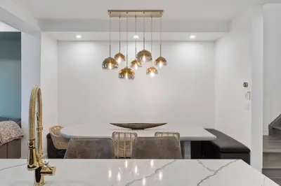 a dining room with a white table and gold chandeliers at Jewel of Blue Mountain - Walk to Ski and Village - EV plug in Blue Mountains