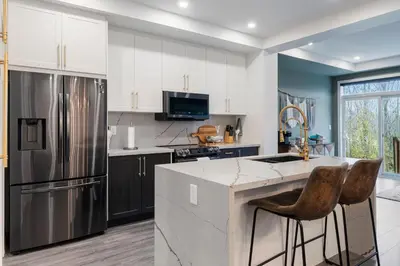 a kitchen with white cabinets and a stainless steel refrigerator at Jewel of Blue Mountain - Walk to Ski and Village - EV plug in Blue Mountains