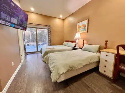 a bedroom with two beds and a tv on the wall at Newly Renovated Home in Central Aurora in Aurora