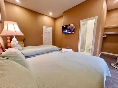 a bedroom with two beds and a tv on the wall at Newly Renovated Home in Central Aurora in Aurora