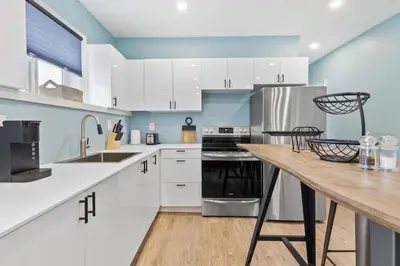 a kitchen with white cabinets and a wooden table at Bright and Spacious Condo in Downtown Collingwood 97043 in Collingwood