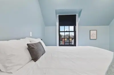 a bedroom with a large white bed with a window at Bright and Spacious Condo in Downtown Collingwood 97043 in Collingwood