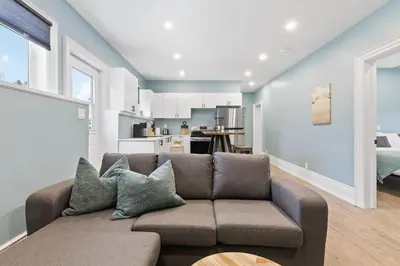 a living room with a couch and a kitchen at Bright and Spacious Condo in Downtown Collingwood 97043 in Collingwood