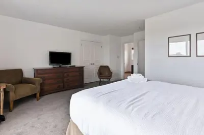 a bedroom with a bed and a tv and a chair at Spectacular Rivergrass Chalet Steps to Blue Mtn in Blue Mountains