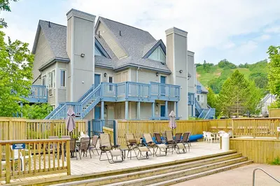 a large house with a deck with chairs and tables at Condo 916 at North Creek Resort in Blue Mountains