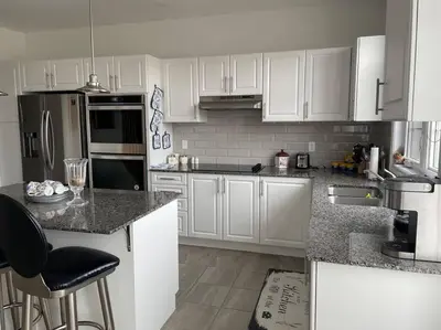 a kitchen with white cabinets and black appliances at Rest in Quinte West - 25 mins from Batawa Ski Hill in Carrying Place
