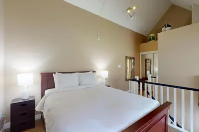 a bedroom with a large white bed and a staircase at Condo 912 at North Creek Resort in Blue Mountains
