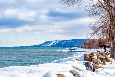 a person walking along a snowy shore next to a body of water at Condo 912 at North Creek Resort in Blue Mountains