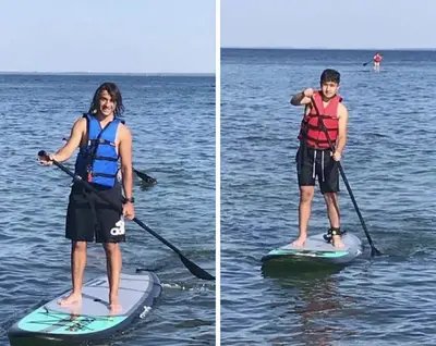 a young girl is standing on a paddle board in the water at Stunning Stayz Luxury 2 King Suite at Friday Harbour Resort Marina Walk & Parking in Innisfil