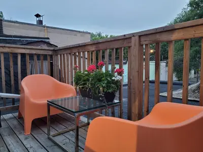 a deck with orange chairs and a table and flowers at Downtown Retreat-Spacious Rooms with Shared Kitchen & Bath in Toronto