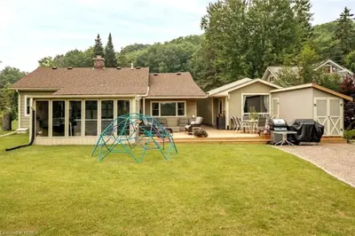 a house with a playground in the yard at Pines Bay Waterfront cottage with Hot tub! in Kawartha Lakes