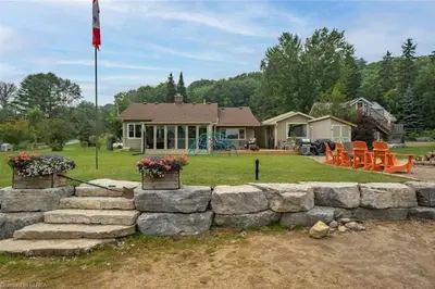 a stone retaining wall in front of a house at Pines Bay Waterfront cottage with Hot tub! in Kawartha Lakes