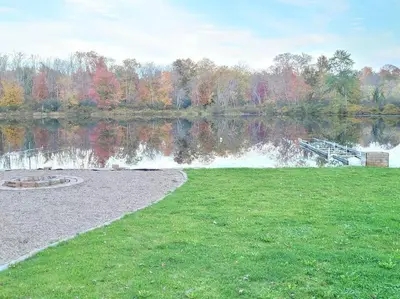 a body of water with a dock in the grass at Pines Bay Waterfront cottage with Hot tub! in Kawartha Lakes